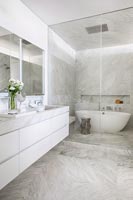 Contemporary white and grey marble bathroom with bath inside glass enclosure 