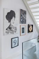 Display of framed modern artwork under stairs