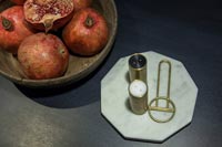 Pomegranates in bowl next to marble tray of condiments on dining table