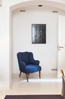 Blue armchair in white hallway 
