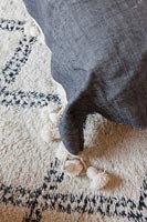 Detail of grey cushion with tassels on black and white rug 