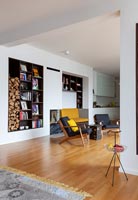 Modern living room with built-in alcove shelving and firewood storage 