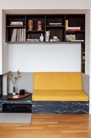 Yellow sofa cushion on built-in seating area in alcove with surrounding shelves 