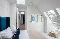 Modern bedroom with pitched roof windows and view along corridor 