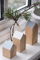 Wooden decorations and cut fir tree branches on windowsill at Christmas 