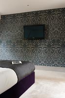 Patterned wallpaper and wall mounted television in modern bedroom 