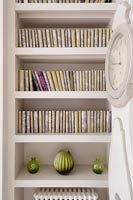 Matching book covers on alcove shelving in muted tones 