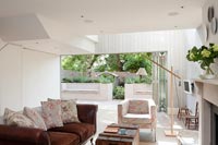 Modern living room with view to courtyard garden through open bifold doors 