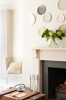 Display of wall mounted plates above fireplace in modern living room 
