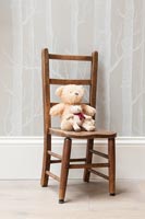 Teddy bear on small wooden chair 