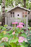 Pink painted wooden playhouse in garden 