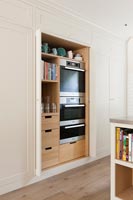 Integrated oven set within shelving unit in modern kitchen 