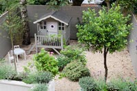 Overhead view of modern courtyard garden with decorative painted wooden playhouse 