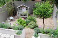 Overhead view of modern courtyard garden with raised painted wooden playhouse 