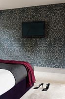 Wall mounted television on patterned wall in modern bedroom 