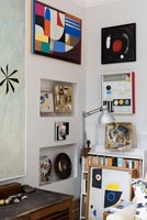 Colourful display of artwork in corner of eclectic living room 