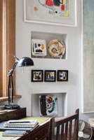 Vintage desk and chair with display of modern artwork on wall of study area 