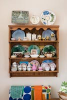 Decorative plates on wooden shelves in small eclectic kitchen  