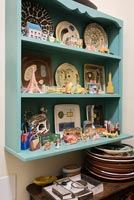 Blue wall mounted shelves covered in plates and small ornaments 