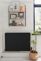 Black radiator against white wall with ornaments on wall mounted shelves