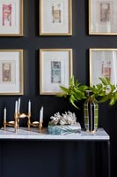 Display of framed pictures on black painted wall with console table 
