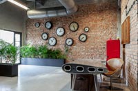 Modern desk and chair with exposed brick wall displaying clocks 