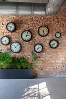 Display of clocks on exposed brick wall 