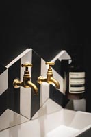 Gold taps over sink in modern black and white bathroom 