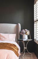 Upholstered headboard in modern bedroom with black painted feature wall 
