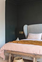 Upholstered headboard in modern bedroom with black painted feature wall 