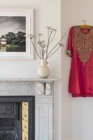 Bright red Indian style dress on wall of living room next to fireplace 
