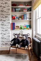 Two matching knitted bears on two-seater wooden chair in childrens room 