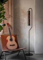 Guitar on leather chair next to modern floor lamp in living room