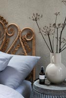 Decorative wicker headboard and dried flowers on bedside table 