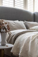 Grey upholstered headboard and linen bedding 