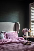 Pink bedding in modern bedroom with black painted walls 