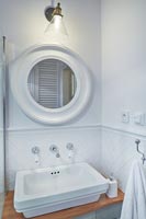 Circular mirror above sink in modern white bathroom 