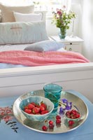 Tray of fruit and drinks on trunk in modern country bedroom 
