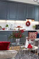 Open plan living space with grey kitchen and red accessories at christmas