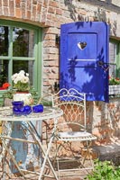 Metal cafe style table and chair outside country cottage 