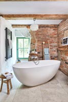 Freestanding bath in centre of modern country bathroom 