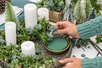 Woman adding Eucalyptus foliage to oasis - making Advent arrangement 