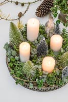 Advent arrangement with white candles, miniature fake Christmas trees