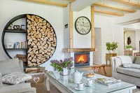 Modern country living room with unusual log storage on wall 
