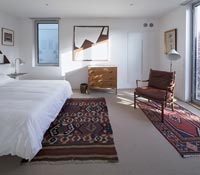 Modern white bedroom with red patterned rugs on floor 