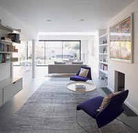 Chairs and side table next to fireplace in modern open plan living space 