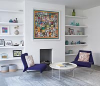 Chairs and side table next to fireplace in modern open plan living space 