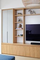 Wooden storage unit and shelves surrounding wall mounted television 