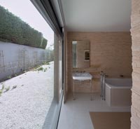 Contemporary bathroom with large open patio door to walled garden 