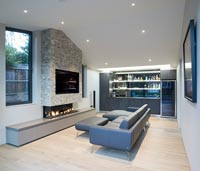 Contemporary living room with bar at one end and large television built-in to fireplace 